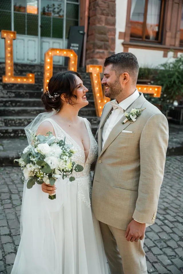 Brautpaar vor leuchtenden LOVE-Buchstaben, Hochzeit auf dem Schlossgut Lüll