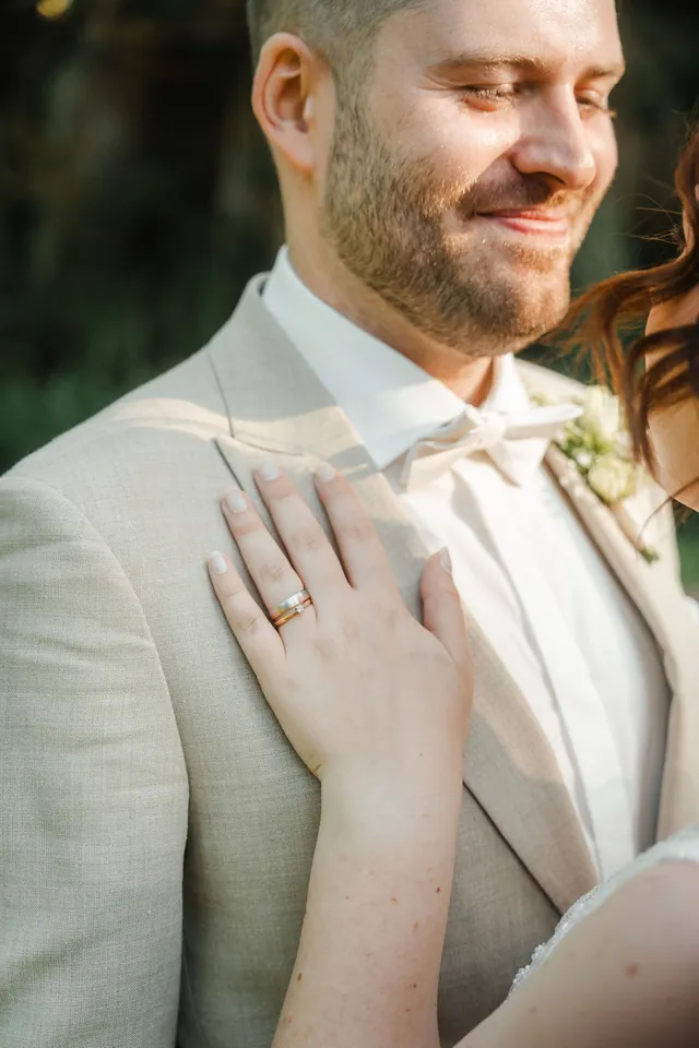 Hand mit Ehering auf der Brust des Bräutigams, Hochzeit auf dem Schlossgut Lüll