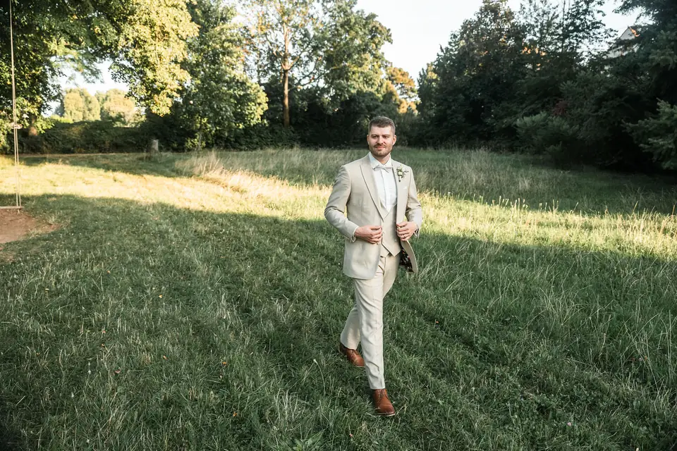 Bräutigam schlendert über die Wiese, Hochzeit auf dem Schlossgut Lüll
