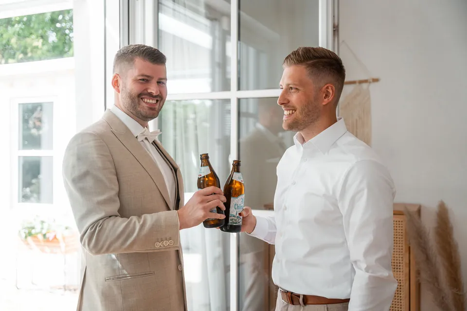 Bräutigam stößt mit seinem Trauzeugen mit Bier an, Hochzeit auf dem Schlossgut Lüll
