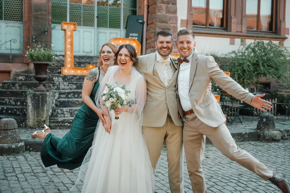 Brautpaar springt vor den LOVE-Buchstaben, Hochzeit auf dem Schlossgut Lüll