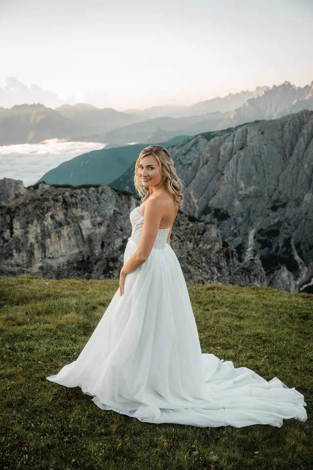 Braut mit ausgebreiteter Schleppe auf der Wiese, After-Wedding-Shooting in den Dolomiten