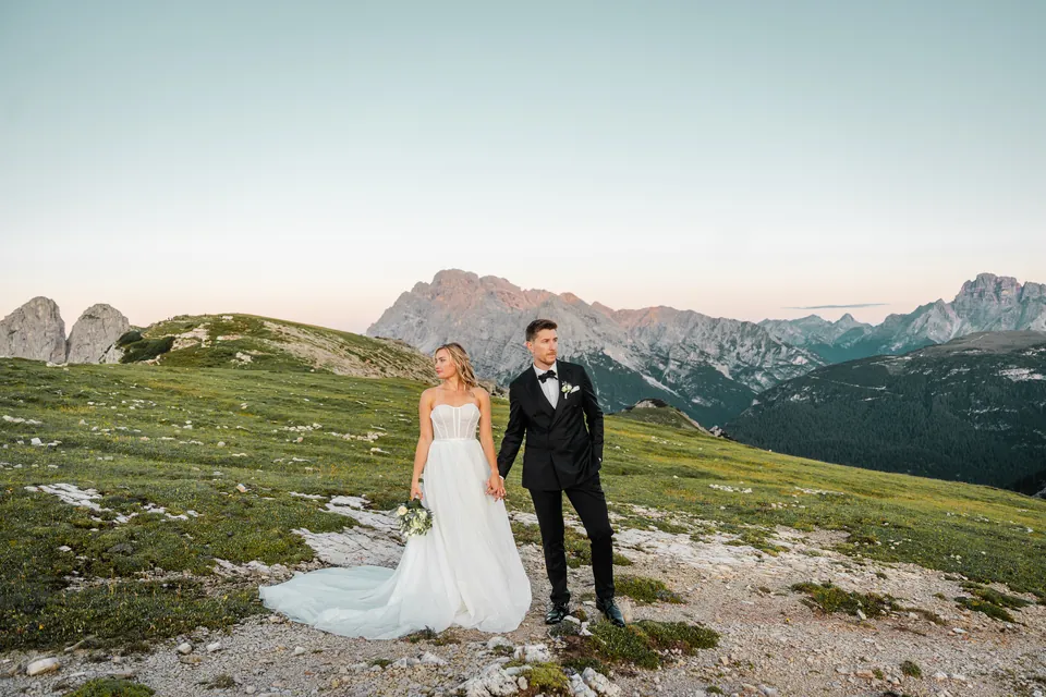Brautpaar Hand in Hand auf der Alm vor dem Bergpanorama, After-Wedding-Shooting in den Dolomiten