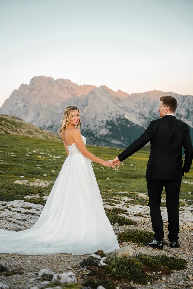 Braut führt den Bräutigam an der Hand, After-Wedding-Shooting in den Dolomiten