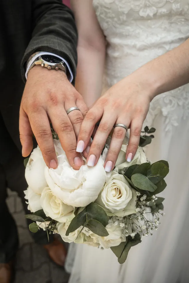 Hände mit Eheringen auf dem Brautstrauß, Hochzeit im Moods