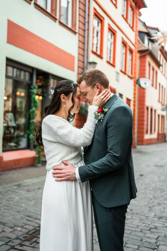 Kim und Jens Stirn an Stirn vor bunten Altstadthäusern, Brautpaarshooting in Heidelberg