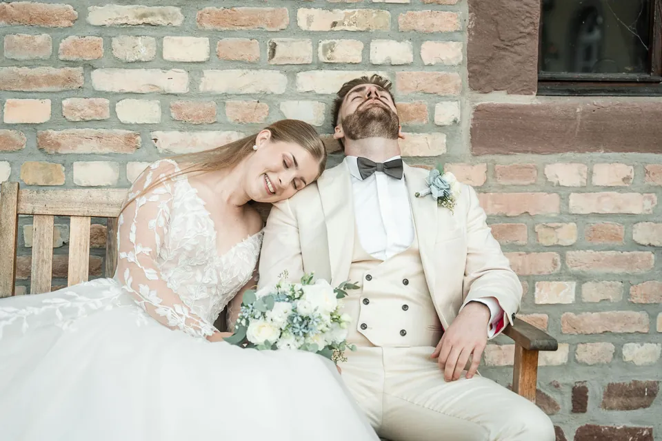 Brautpaar auf einer Bank vor der Steinmauer, Hochzeit in der Schleifenmühle Dettenheim-Rußheim
