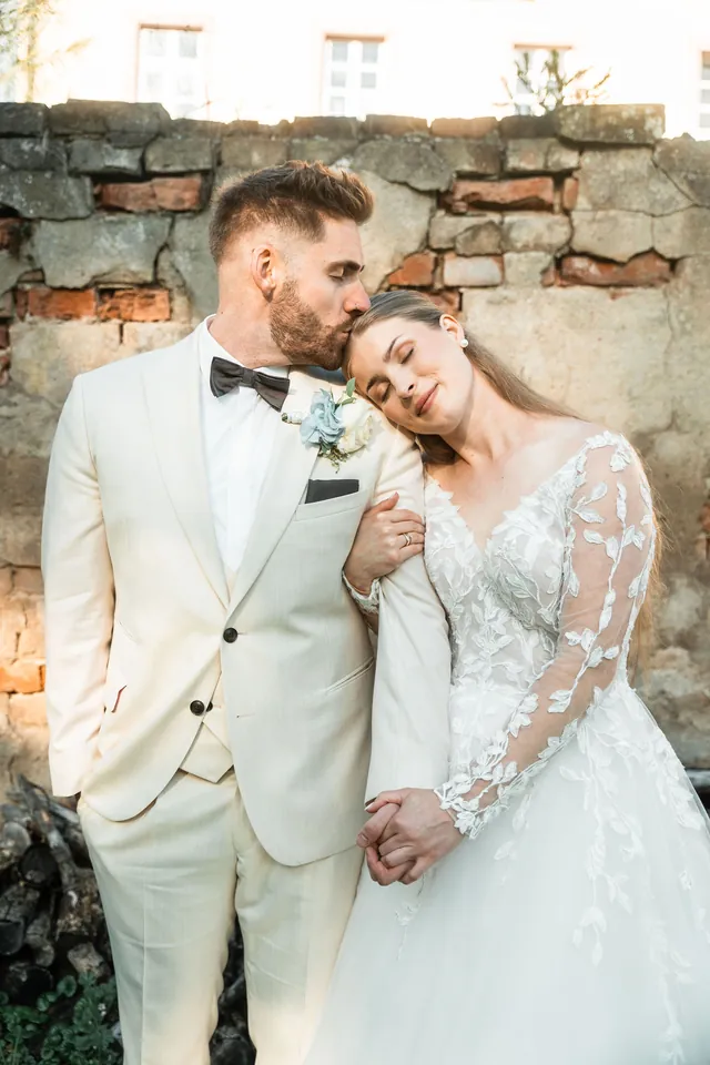Melanie legt den Kopf an Robins Schulter vor der alten Steinmauer, Hochzeit in der Schleifenmühle Dettenheim-Rußheim bei Karlsruhe