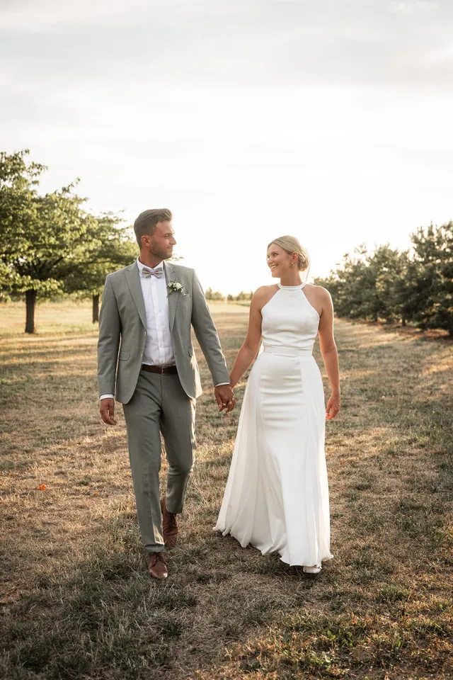 Brautpaar Hand in Hand zwischen den Bäumen im Abendlicht, Hochzeit im Eichenstolz Ladenburg