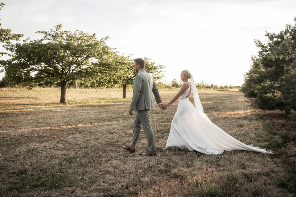 Brautpaar Hand in Hand über das Feld im Abendlicht, Hochzeit im Eichenstolz Ladenburg