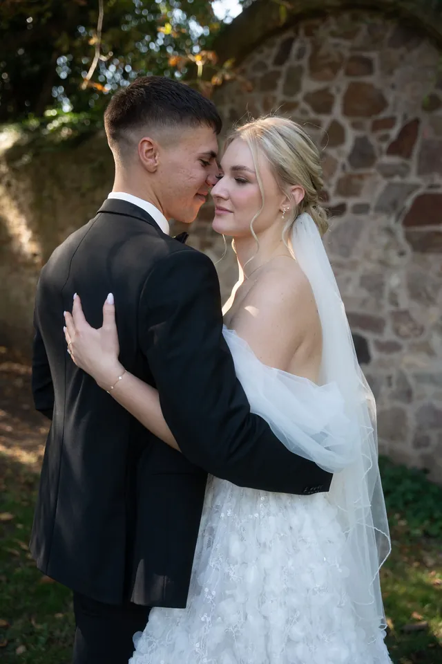Brautpaar Wange an Wange vor der Steinmauer, Hochzeit am Schloss Schwetzingen