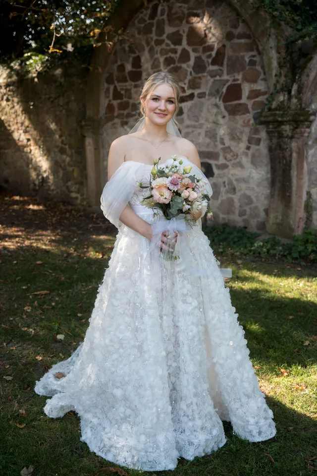 Braut mit Brautstrauß an der Steinmauer, Hochzeit am Schloss Schwetzingen