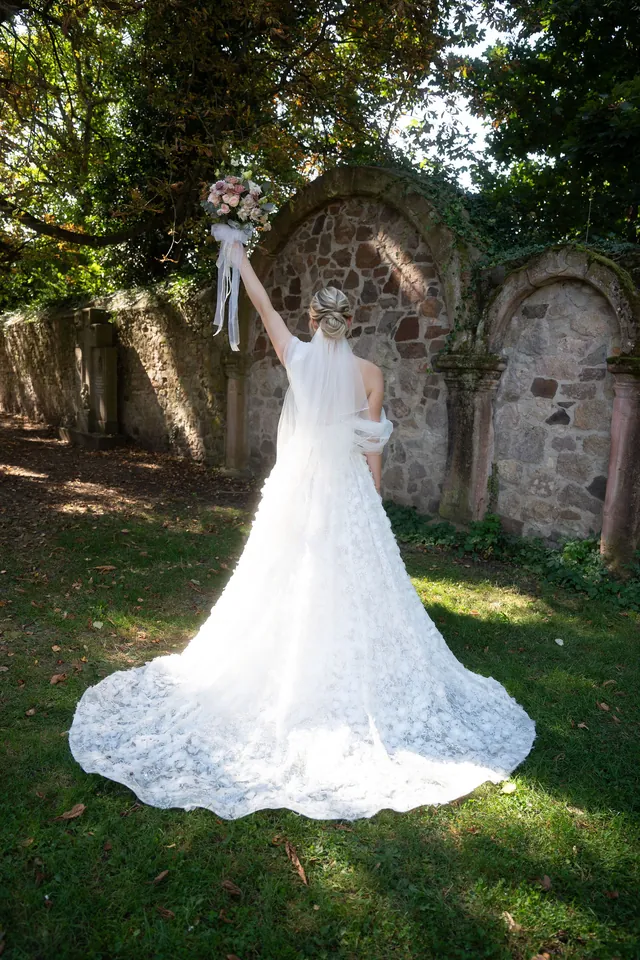 Braut hebt den Brautstrauß in die Luft, Hochzeit am Schloss Schwetzingen