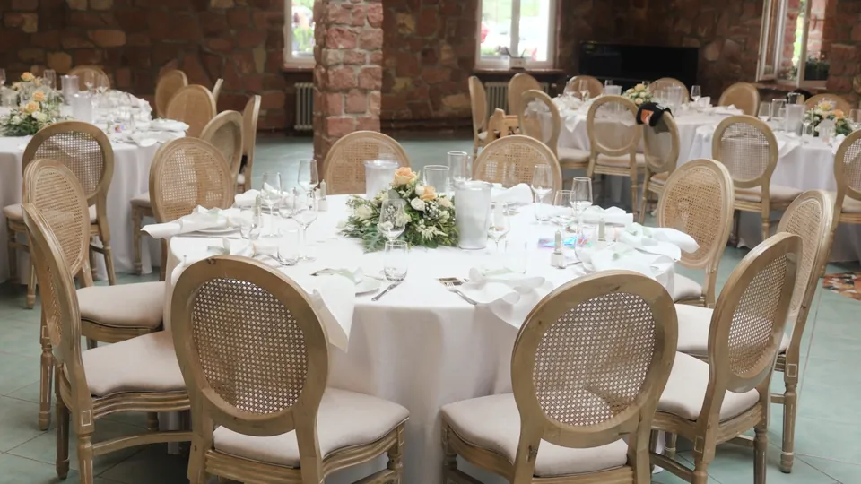 Gedeckte runde Tafeln mit Rattanstühlen im Festsaal aus Buntsandstein, Wilhelmsgut Heidelberg